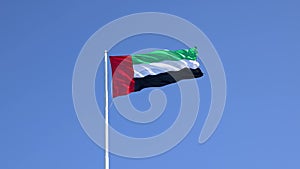 UAE flag waving in the blue sky, national symbol of UAE