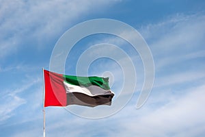 UAE flag waving in the sky, national symbol of UAE. UAE National Day.