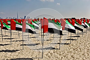 UAE National Flag Day. On a sandy beach, a composition of many flags