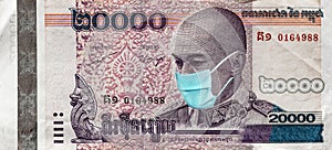 Uarantine and global recession. 20000 Riel banknote with a face mask against infection