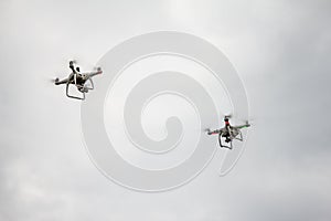 UAV two white drones Quadr copter in flight with and digital camera explores the area on the background of a sunset with clouds.