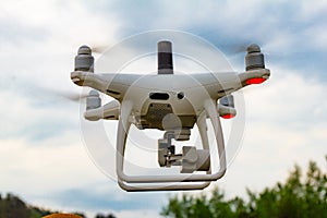 UAV White drone Quadr copter in flight with geodesic module and digital camera explores the area on the background of a sunset