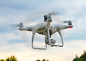 UAV White drone Quadr copter in flight with geodesic module and digital camera explores the area on the background of a sunset