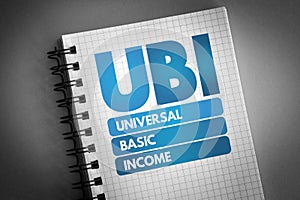 UBI - Universal Basic Income acronym on notepad, concept background photo