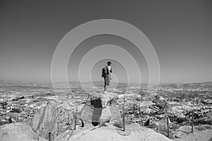 Uchisar Castle. Tourist at the top of the fortress, mountains, view of Cappadocia. Man photographer, male Traveler at Destinaton.