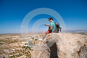 Uchisar Castle. Tourist at the top of the fortress, mountains, view of Cappadocia. Man photographer, male Traveler at Destinaton.