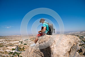 Uchisar Castle. Tourist at the top of the fortress, mountains, view of Cappadocia. Man photographer, male Traveler at Destinaton.