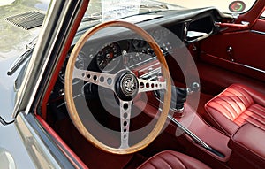 Wooden steering wheel and black dashboard of Jaguar E-Type , british sports car from Sixties.