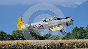 Old military airplane of WWII landing with mountains in the background