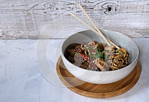 Udon bowl with chicken breast and vegetables top view with soy sauce and sicks. Asian food. Place for text photo