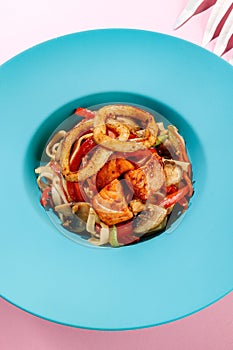 Udon with calamary and vegetables, seafood on blue pastel color plate at white background with sunlight and shadows, minimalism,