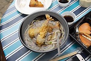 Udon noodles or noodle soup japanese style topping with crispy tempura prawns on table
