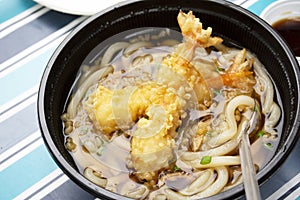 Udon noodles or noodle soup japanese style topping with crispy tempura prawns on table