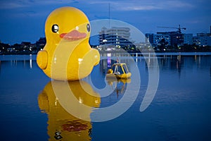 Yellow giant inflatable duck and yellow boat on the lake in Nong Prajak Park at night