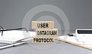 UDP - User Datagram Protocol text on wooden block with notebook,chart and calculator, grey background