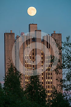 Uenusually large moon over the skyscraper in a summer evening sky.