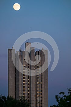 Uenusually large moon over the skyscraper in a summer evening sky.