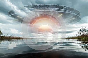 UFO, an alien saucer hovering above the lake in the clouds, hovering motionless in the sky. Unidentified flying object, alien