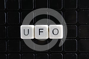 UFO control text word title caption label cover backdrop background. Alphabet letter toy blocks on black reflective background. photo