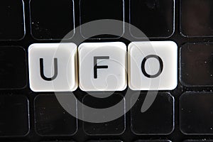 Ufo,title text word crossword. Alphabet letter blocks game texture background. White alphabetical letters on black