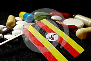 Ugandan flag with lot of medical pills isolated on black background