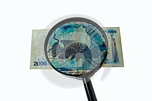 Ugandan shillings bill and magnifying glass