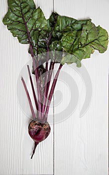 Ugly beetroot on a light wooden background.