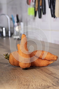 Ugly Carrot in the kitchen worktop, blurred background. Soft focus