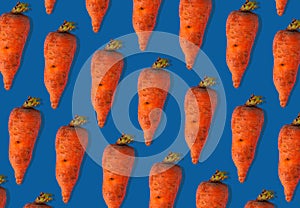 Ugly carrots regular pattern with shadows pastel background. Big deformed vegetables on pastel background.Trendy flatlay