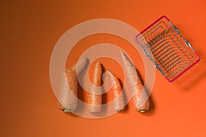Ugly food. Deformed organic carrots on an orange background. Food waste concept in food basket. Minimalism, pop art