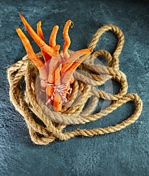 Ugly food. Deformed organic carrots on a rope on a blue background. Deformed products, food waste problem concept