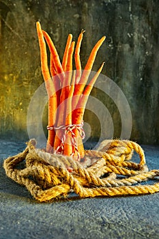 Ugly food. Deformed organic carrots on a rope on a blue background. Deformed products, food waste problem concept