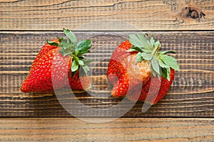 Ugly fruit. Misshapen produce concept. Organic deformed strawberries on wood background