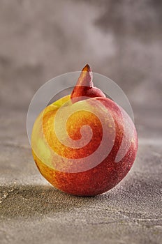 Ugly fruit or vegetable. Severely malformed mutant peach on grey background. Ugly fruit is not in high demand