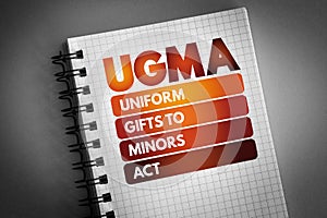 UGMA - Uniform Gifts to Minors Act acronym on notepad, concept background