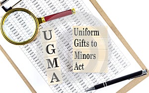 UGMA - Uniform Gifts to Minors Act text on wooden block on chart background