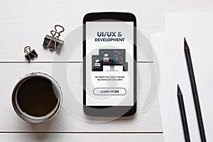 UI/UX design and development concept on smart phone screen with office objects