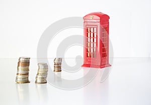 UK Brexit. piles of coins with an English telephone booth on a white background