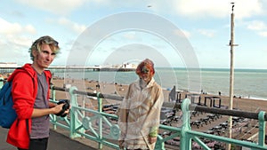 UK, Brighton. Young hipster couple taking photo on the coast. Happy lovers, woman and man traveling on vacation on ocean