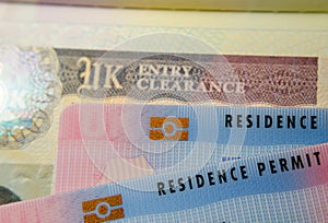 UK BRP Biometrical Residence Permit cards for Tier 2 work visa placed on top of United Kingdom Entry Clearance vignette sticker