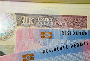 UK BRP Biometrical Residence Permit cards for Tier 2 work visa placed on top of United Kingdom Entry Clearance vignette sticker photo