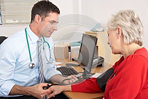 UK doctor taking senior woman's blood pressure