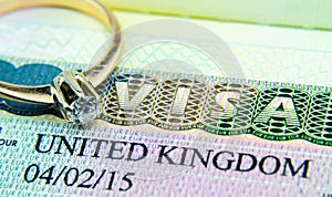 UK entry visa sticker in a passport and the engagement ring placed on top. Conceptual photo for fiance / spouse visa and