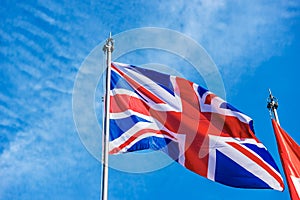 UK Flag Blowing in the Wind on Blue Sky with Clouds - Union Jack Flag