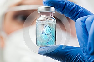 UK lab scientist biotechnologist holding glass ampoule vial with DNA strand