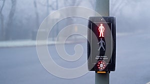 UK traffic crossing with Red man and crossing button Illuminated on a cold foggy day