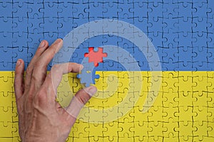 Ukraine flag is depicted on a puzzle, which the man`s hand completes to fold