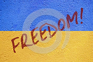 Ukraine flag painted on old concrete wall with FREEDOM inscription