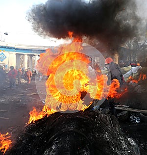 Ukraine. Kiev. Revolutionaries in helmets and masks near flaming tires.