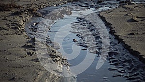 Ukraine, Kuyalnik Liman, water flows out of mud baths and flows into Kuyalnik Liman, black silt in waves at the bottom of the